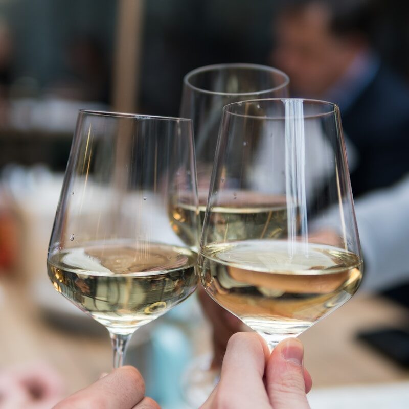 three people having a toast using three clear crystal wine glasses